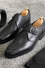 Elegant black leather single monk strap loafers with sleek design, buckle closure, and timeless style.