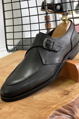 Elegant black leather single monk strap loafers with sleek design, buckle closure, and timeless style.
